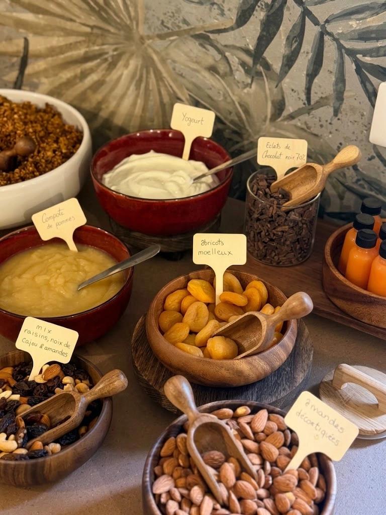 Une vue de dessus en plongée d'un buffet de petit-déjeuner rustique et élégant sur un comptoir en pierre texturée. La scène présente une variété de bols artisanaux en bois et en céramique rou