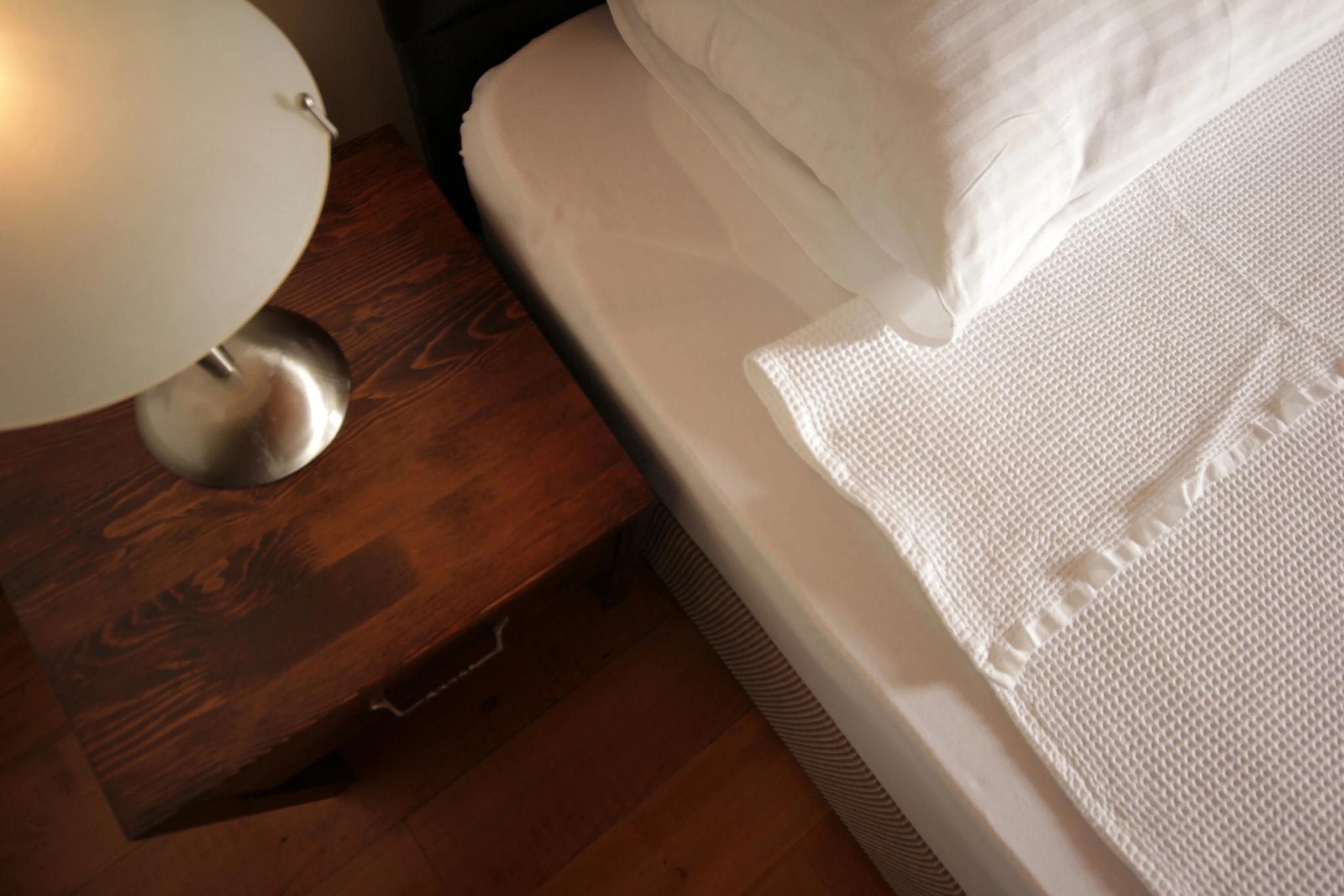 Détail de la literie et table de chevet dans une chambre de l'hôtel 4 étoiles 